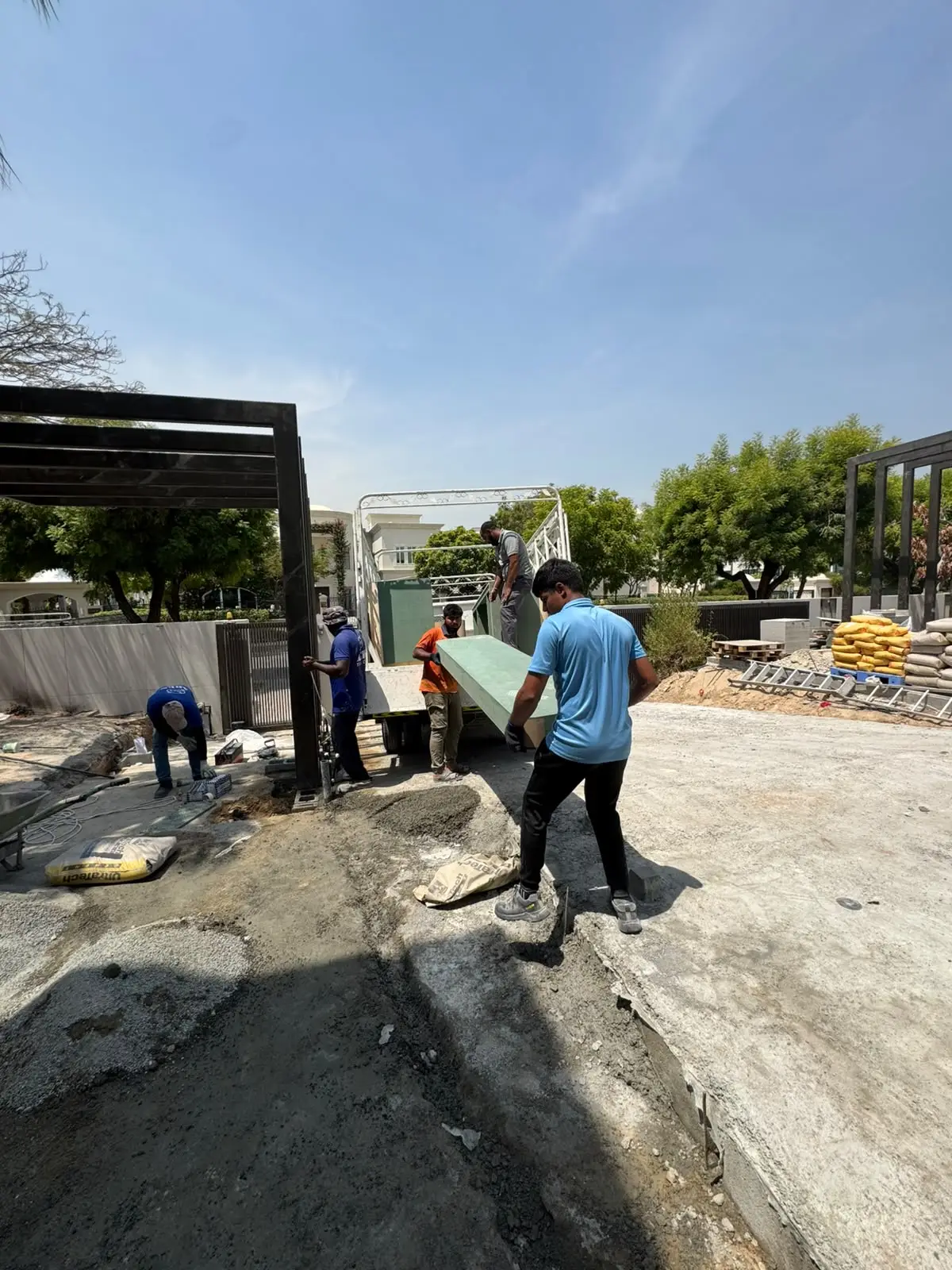 Workers carrying construction debris panel at outdoor site in Dubai